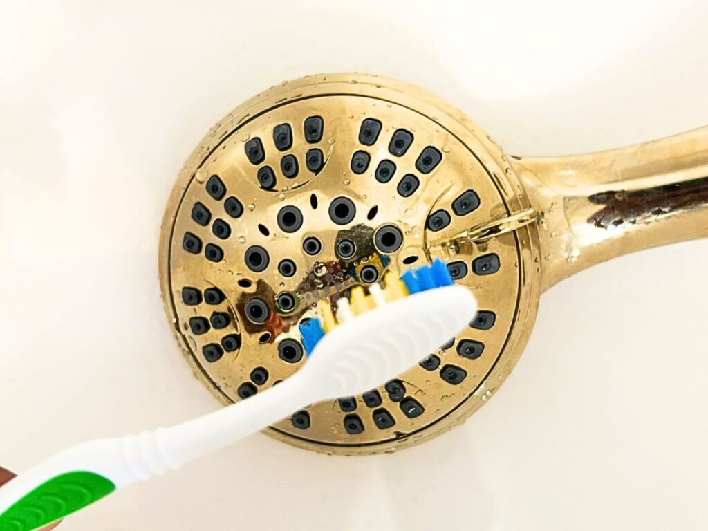 cleaning shower head with toothbrush