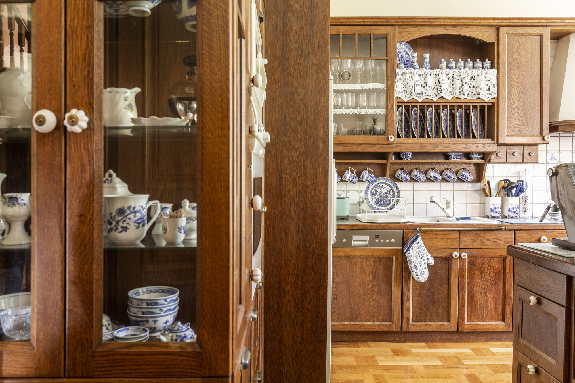Old fashioned wooden cabinets with white and cobalt blue china in kitchen interior.