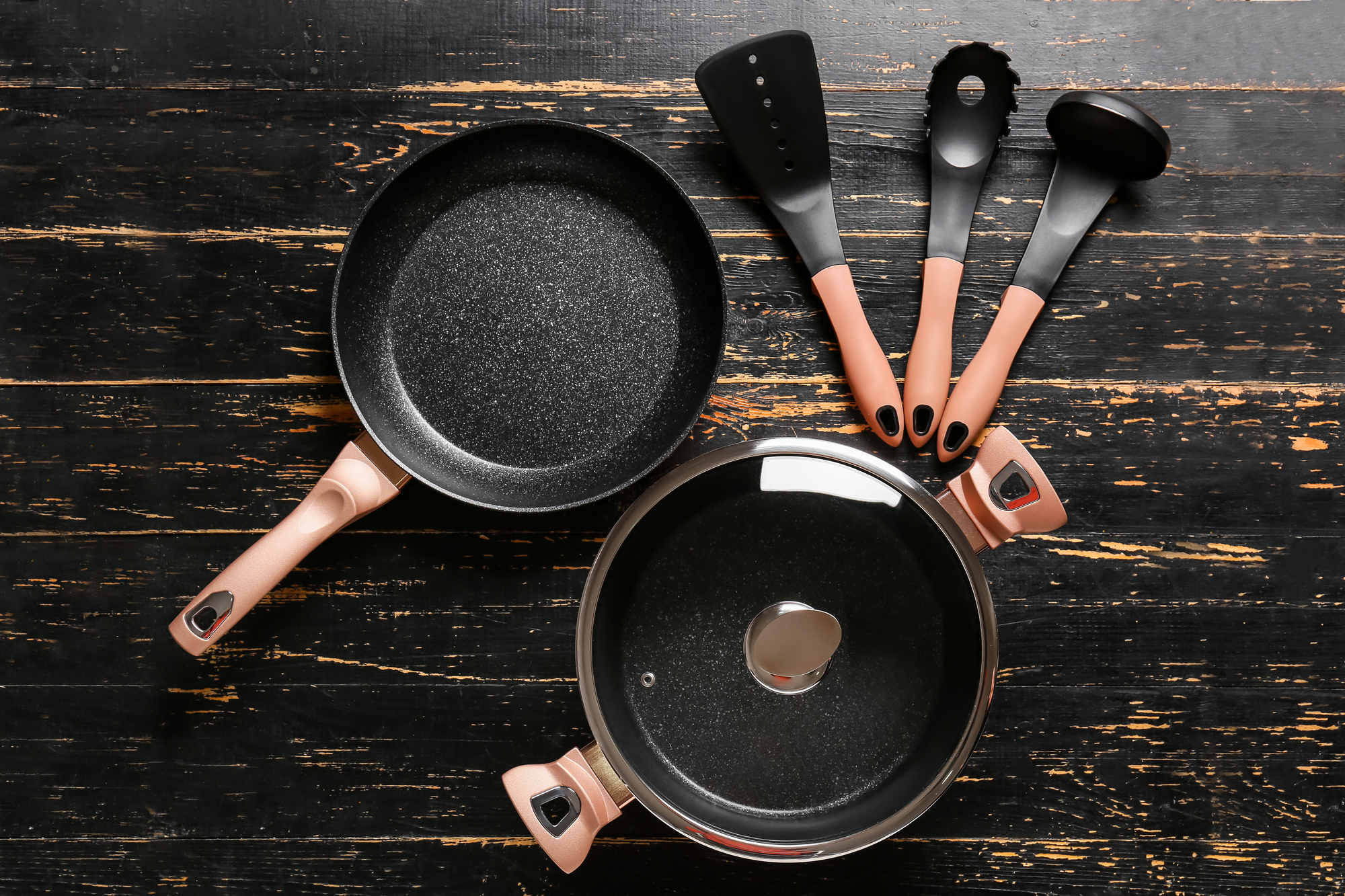 Cooking pot, frying pan and kitchen utensils on dark wooden non stick