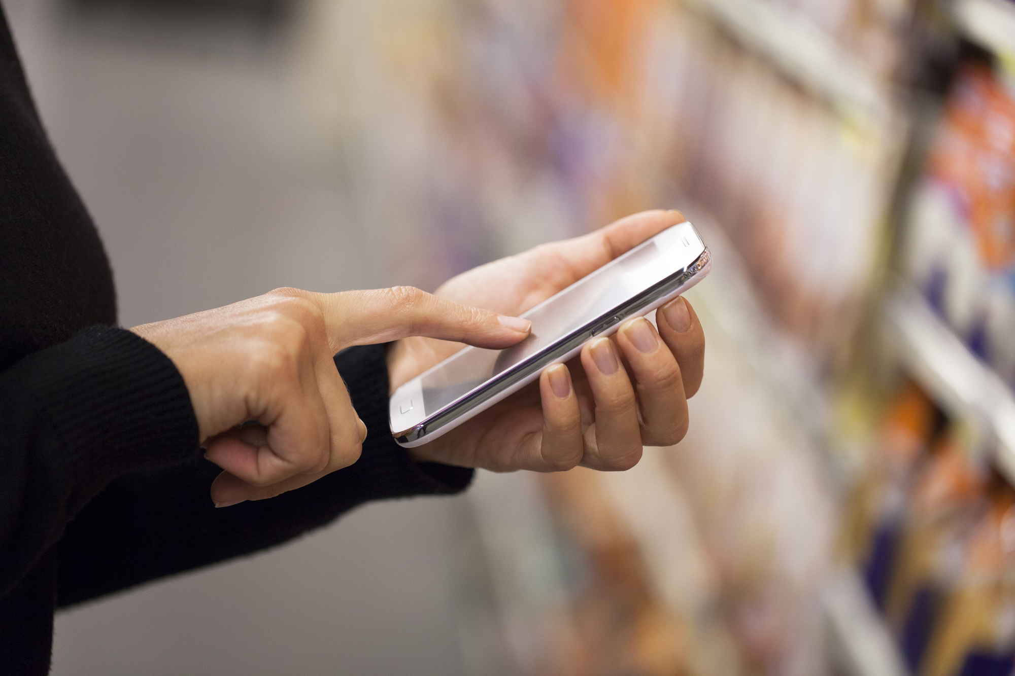 Woman using mobile phone while shopping in supermarket