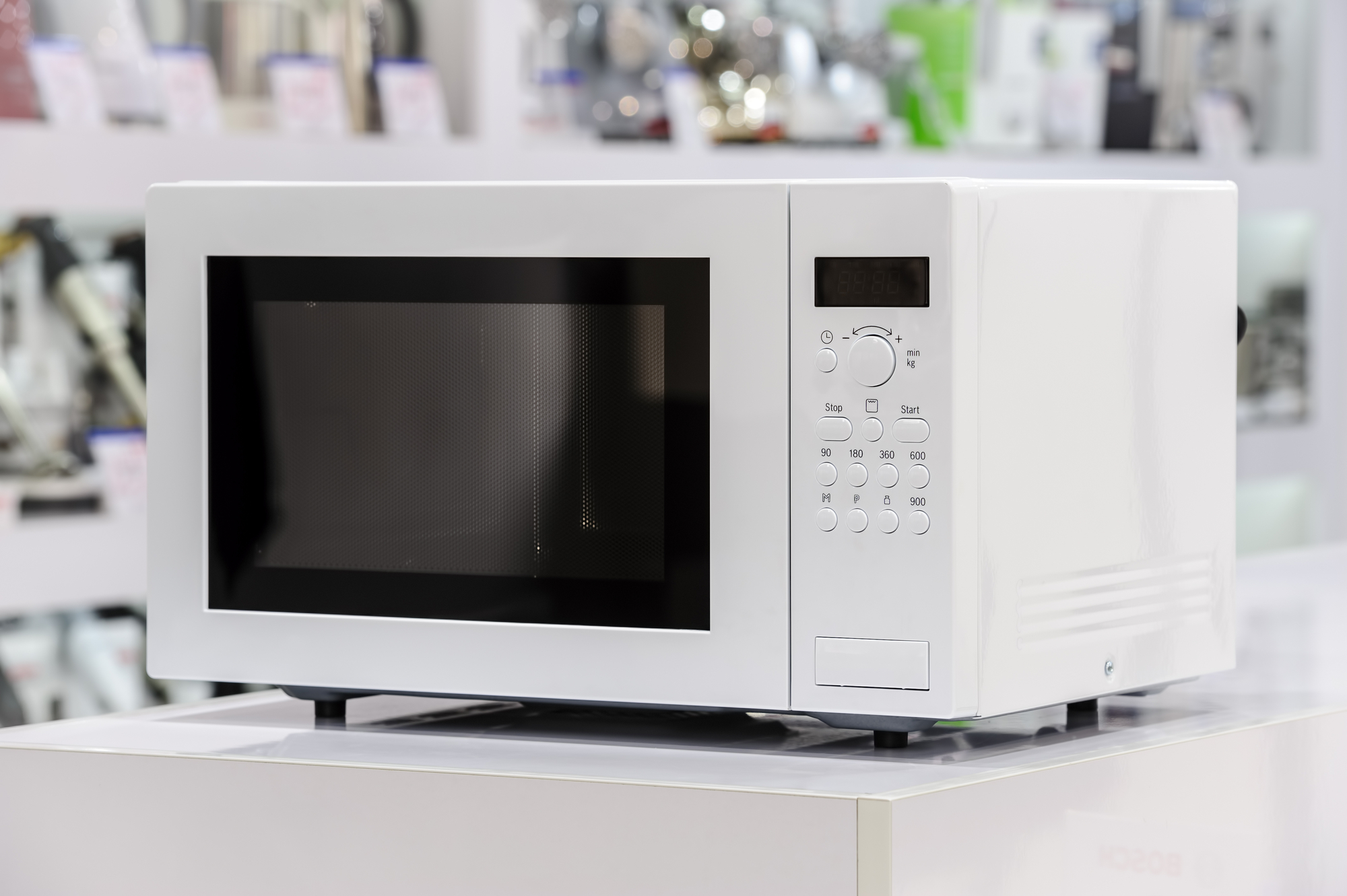 single white microwave oven at retail store shelf, defocused background