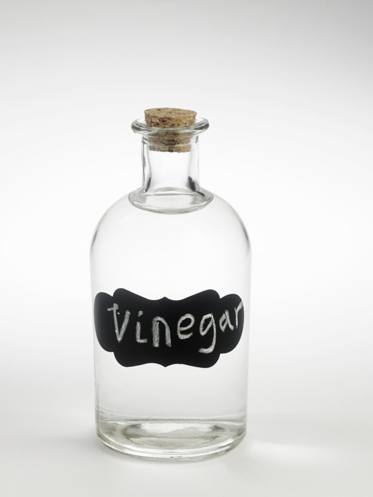 White vinegar in a glass bottle. White background.