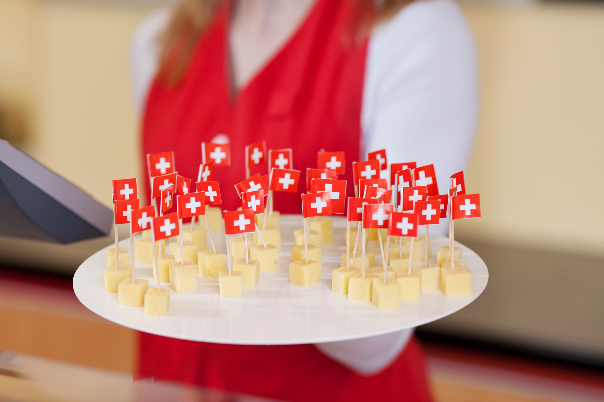 Close-up image of a female worker offering cheese cubes for tasting.