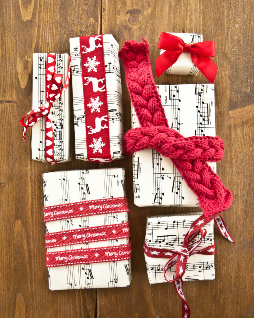 Little boxes wrapped in sheet music and red ribbons on wood