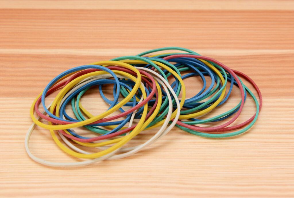 Large pile of colored elastic bands on a wooden background