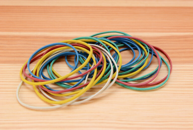 Large pile of colored elastic bands on a wooden background