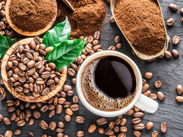 Roasted coffee beans, ground coffee and cup of coffee on wooden table. Top view.
