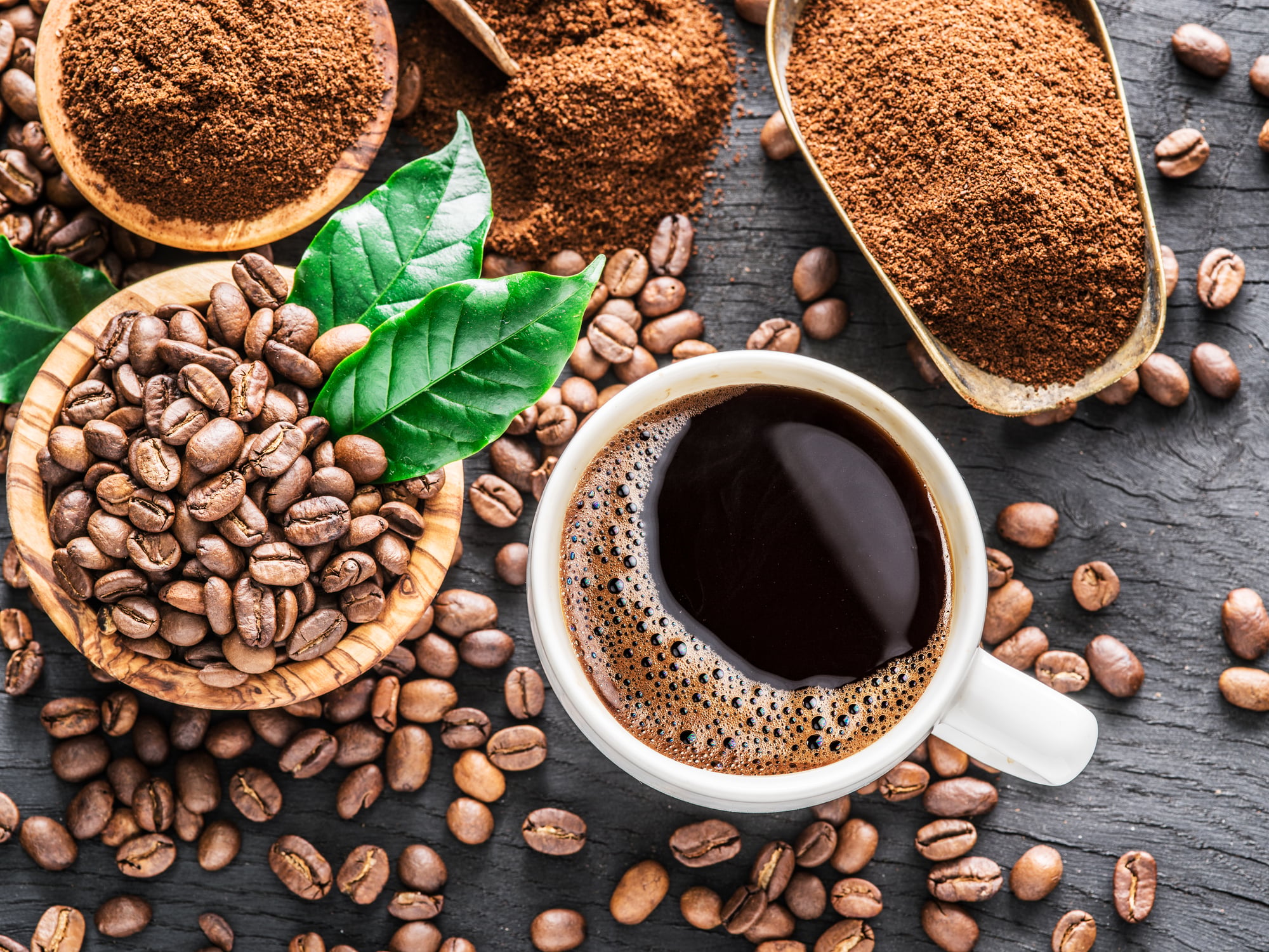 Roasted coffee beans, ground coffee and cup of coffee on wooden table. Top view.