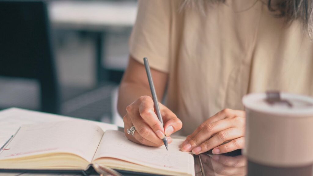 The Woman Is Writing In Her Notebook
