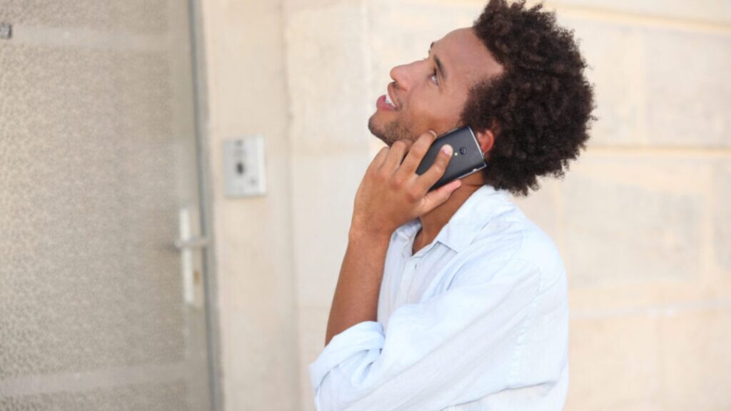 A man at phone in front of a closed door
