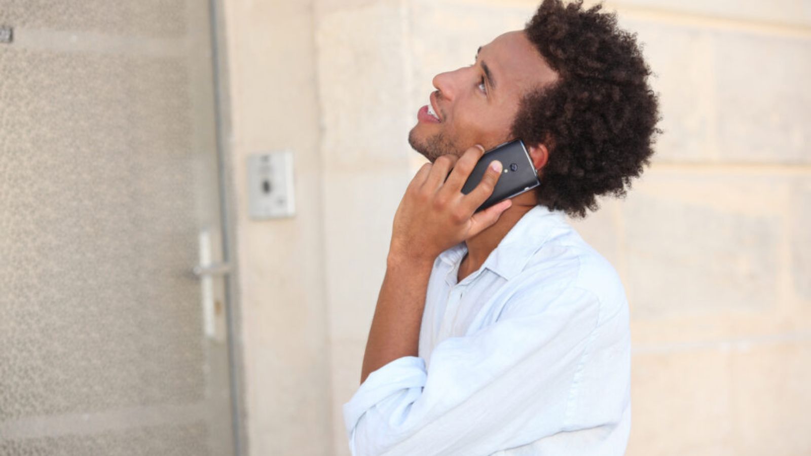 A man at phone in front of a closed door