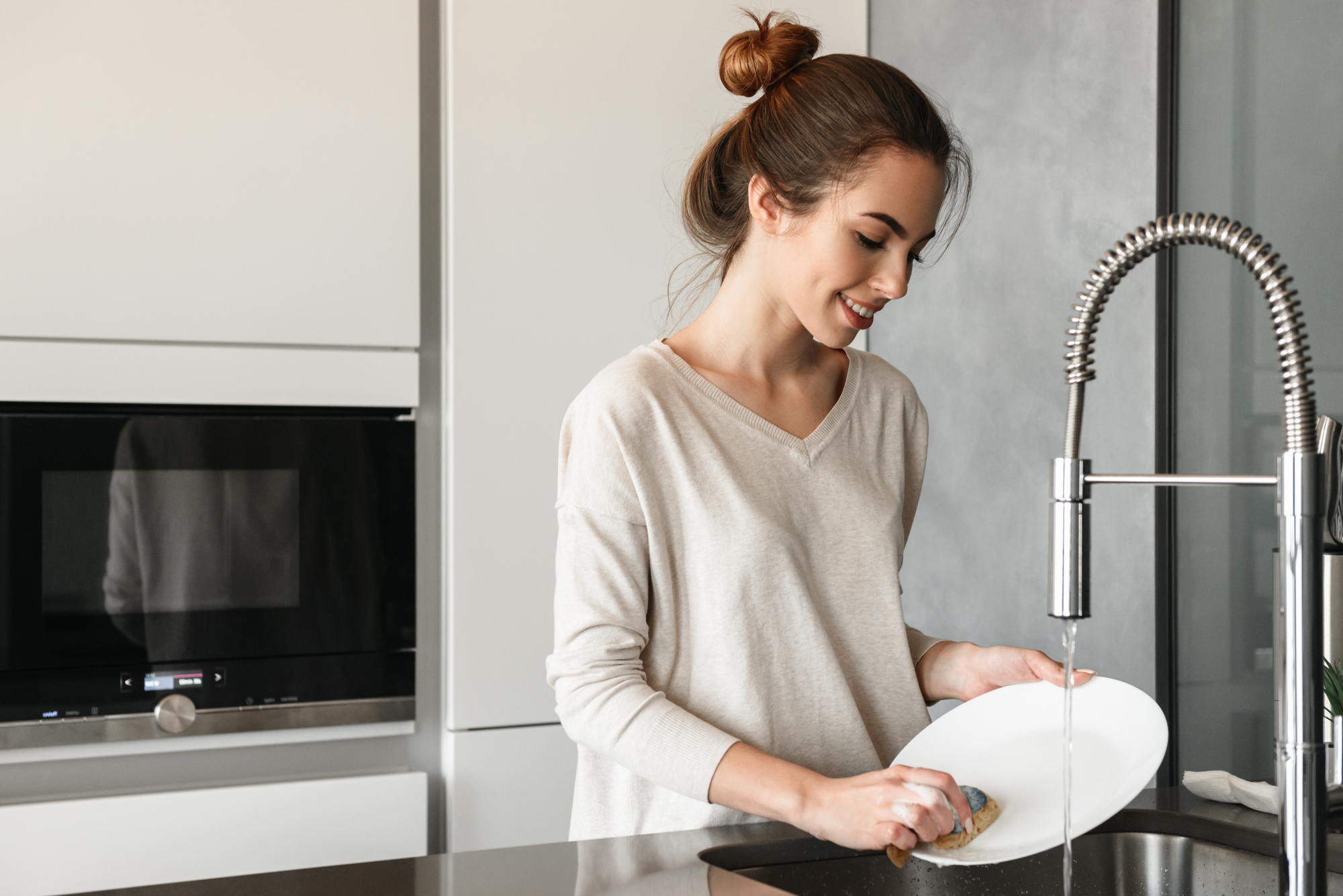 Portrait of a smiling young woman washing dishes