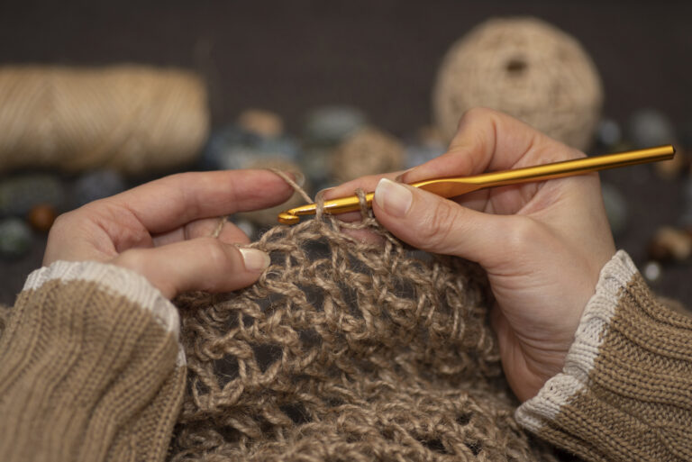 Female hands crafting knitting with crochet. Hobbies, handicrafts and handmade work. Threads, balls of yarn, skeins, bobbins, spools.