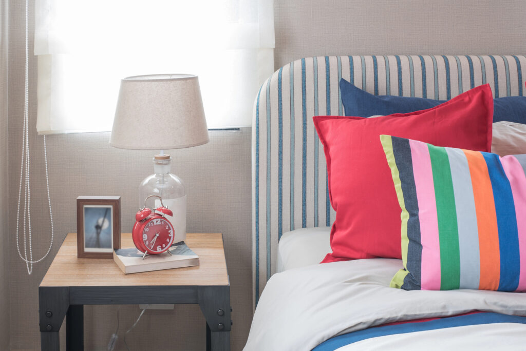 bedroom with colorful pillows and side table