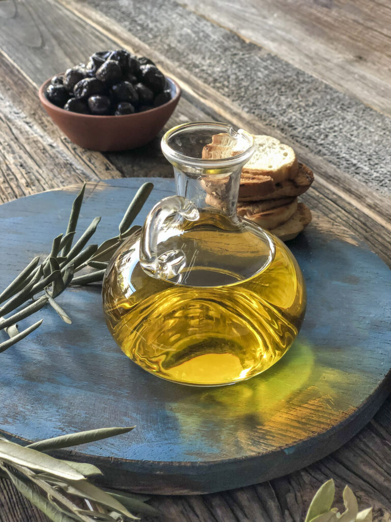 a bottle of olive oil and olives on a wooden table
