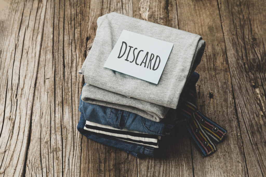 Stack of old clothes to discard (declutter) or donate. Recycling fabric cotton.