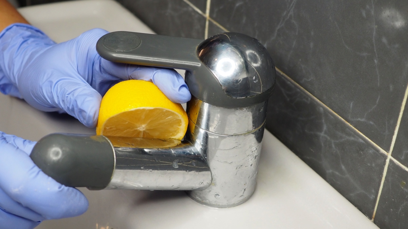 Man-cleaning-stainless-steel-faucet-with-lemon