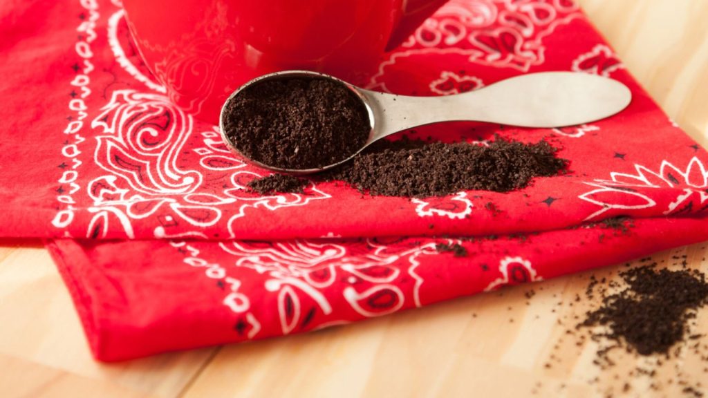 Red coffee mug with napkin and grounds.