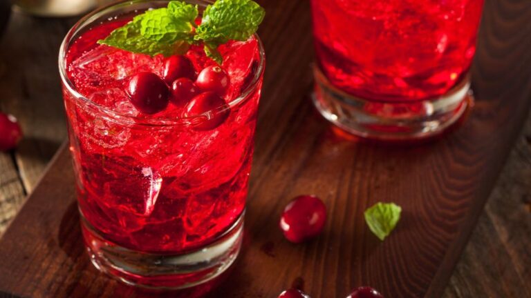 Three glasses of cranberry cocktail on a wooden table.