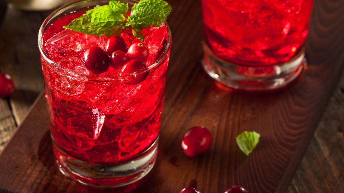 Three glasses of cranberry cocktail on a wooden table.