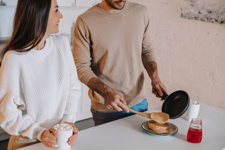 woman and man in kitchen making pancakes cooking