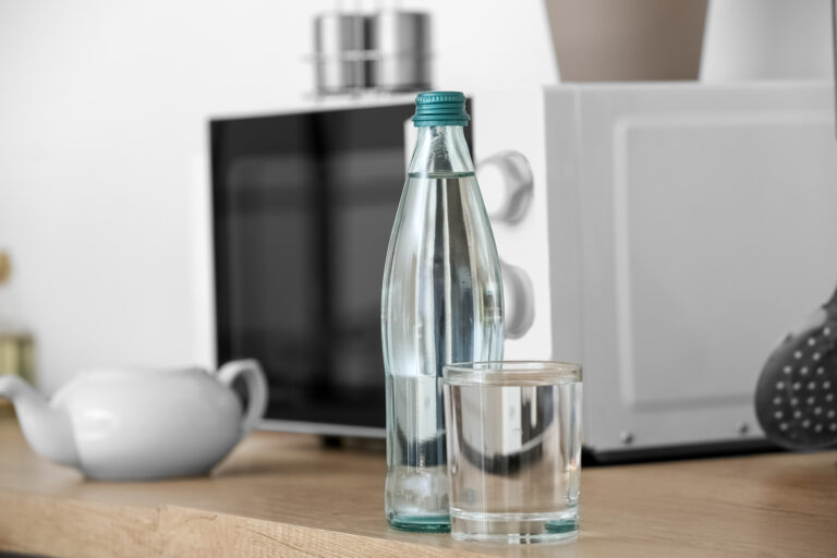 Bottle and glass of clean water on kitchen counter