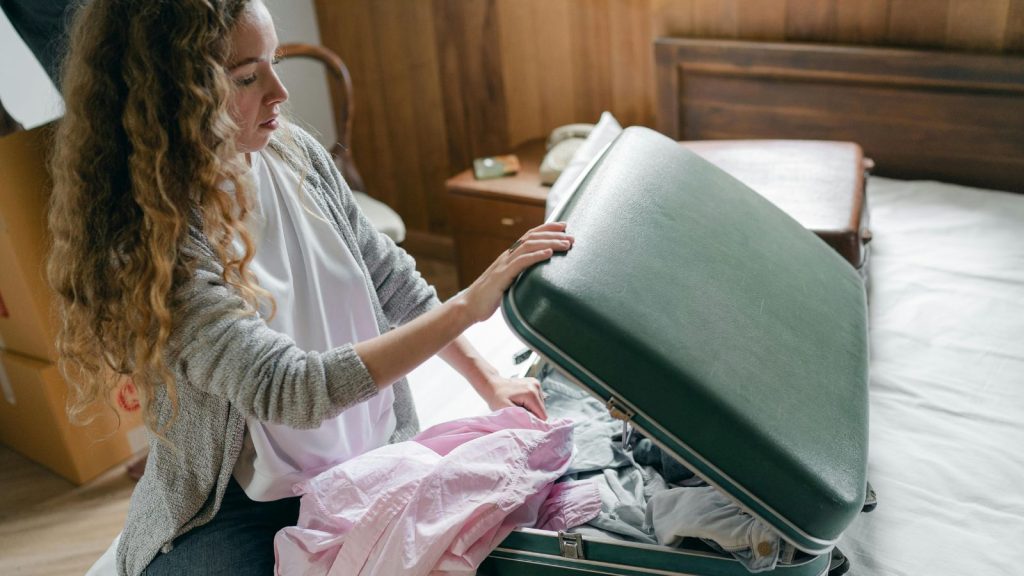 Focus woman packing suitcase on bed