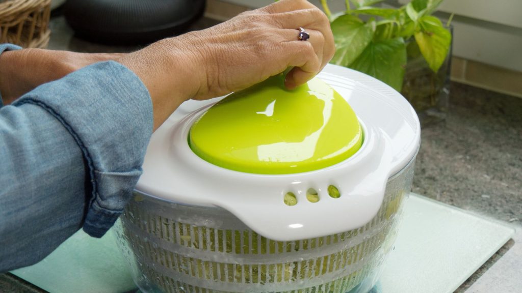 a hand of a woman spinning salad
