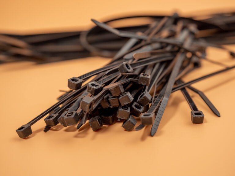 Black plastic cable ties on an orange background.