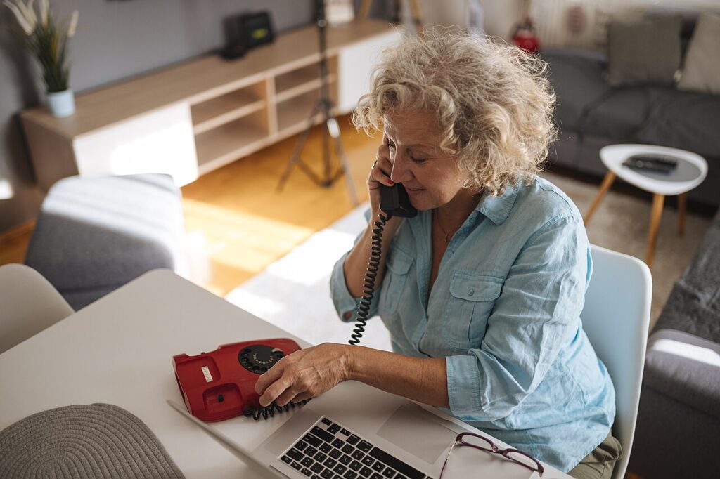 1280px Woman on phone while working on laptop in cozy living room