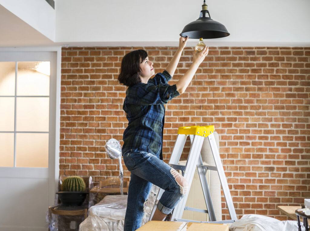 woman changing lightbulb in living room on ladder
