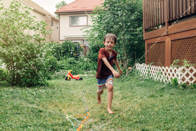 kid running around in water hose