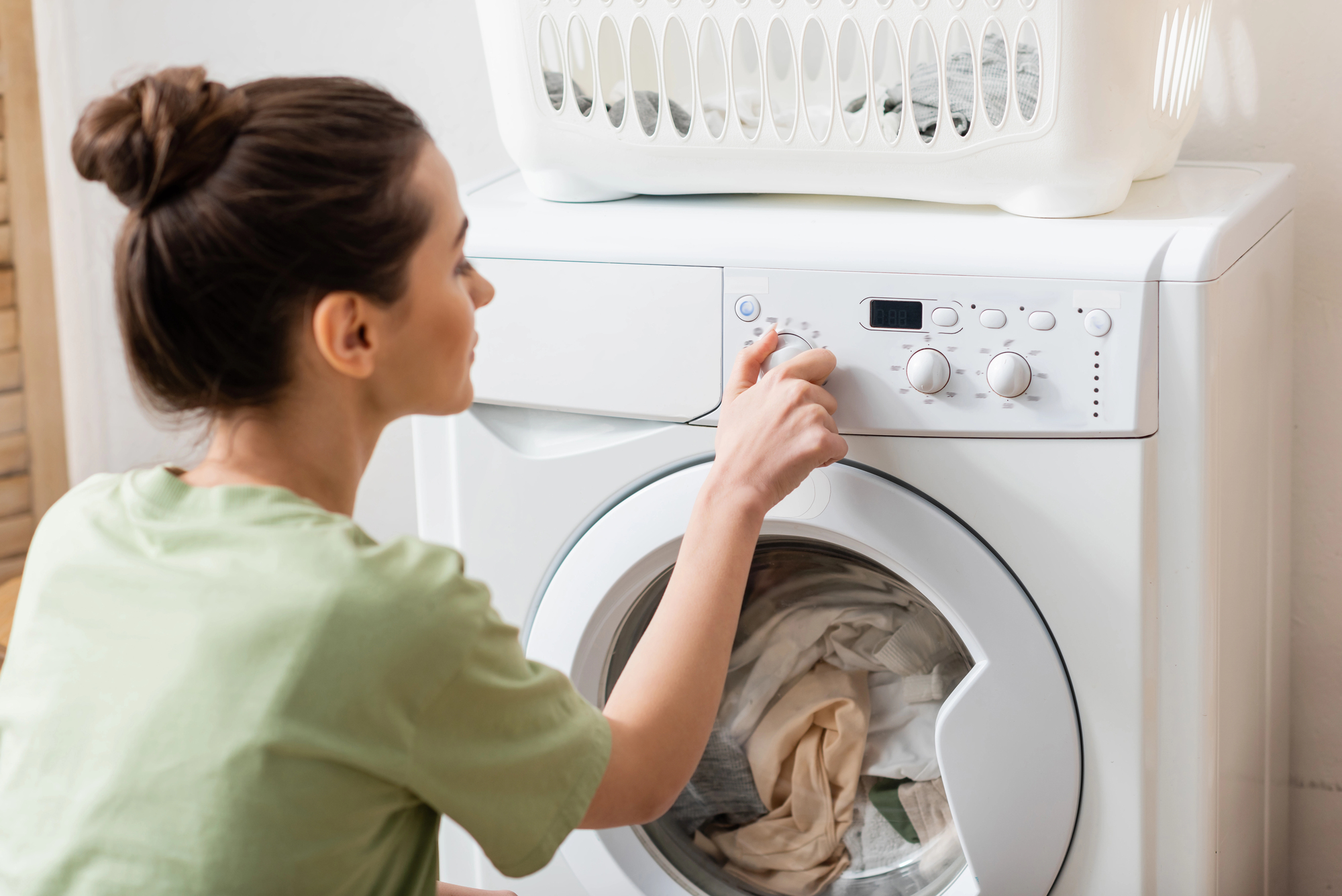 woman turning the washing machine on