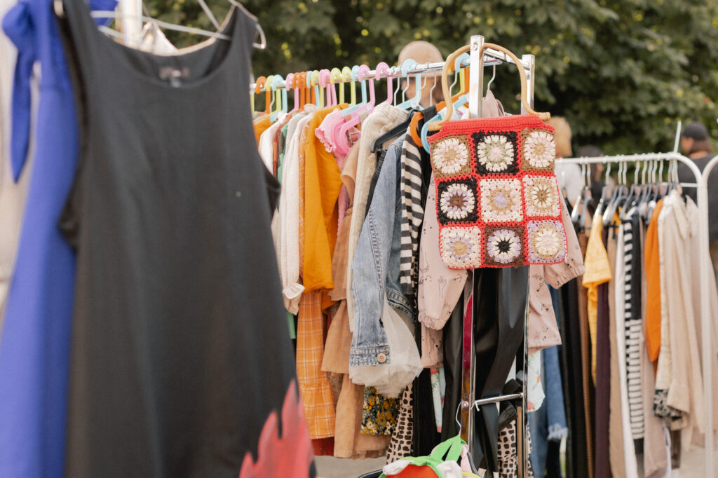 garage sale Choice of fashion clothes of different colors on hangers in a retail shop. Flea market with old clothes outside. Reduce Reuse Recycle concept