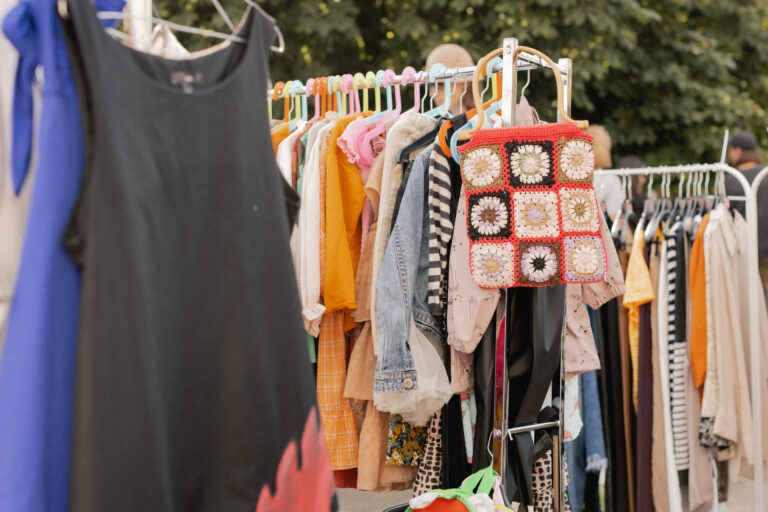 garage sale Choice of fashion clothes of different colors on hangers in a retail shop. Flea market with old clothes outside. Reduce Reuse Recycle concept