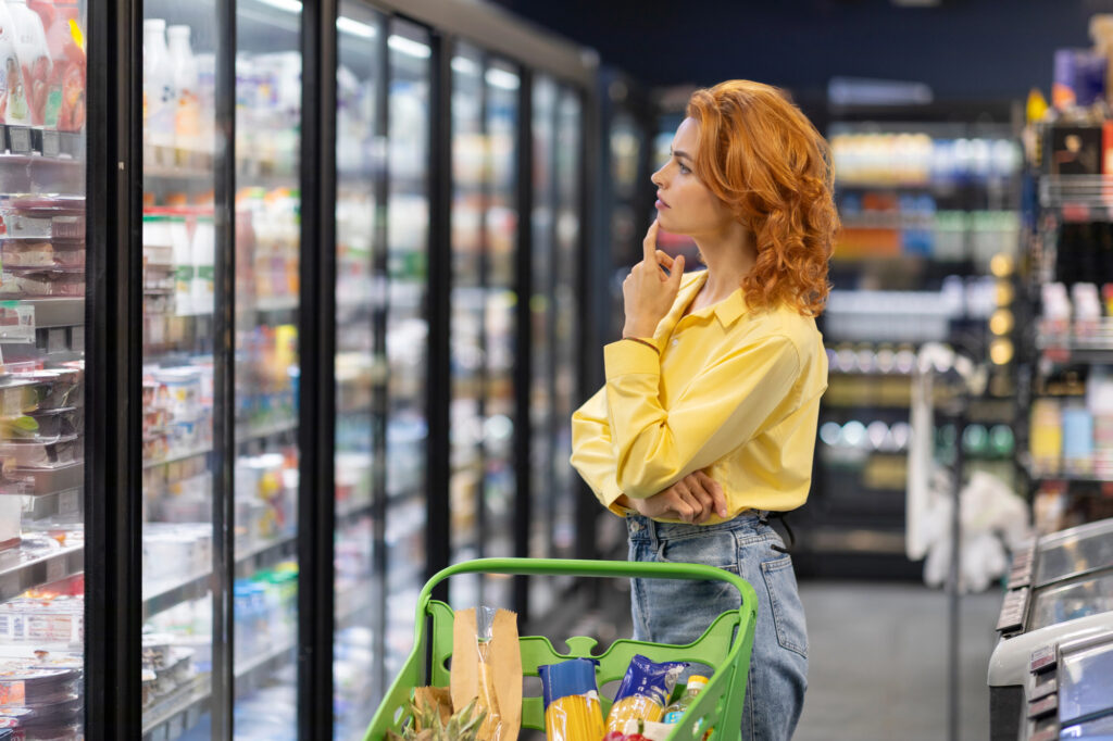 redhead lady thinking about what to buy at supermarket grocery