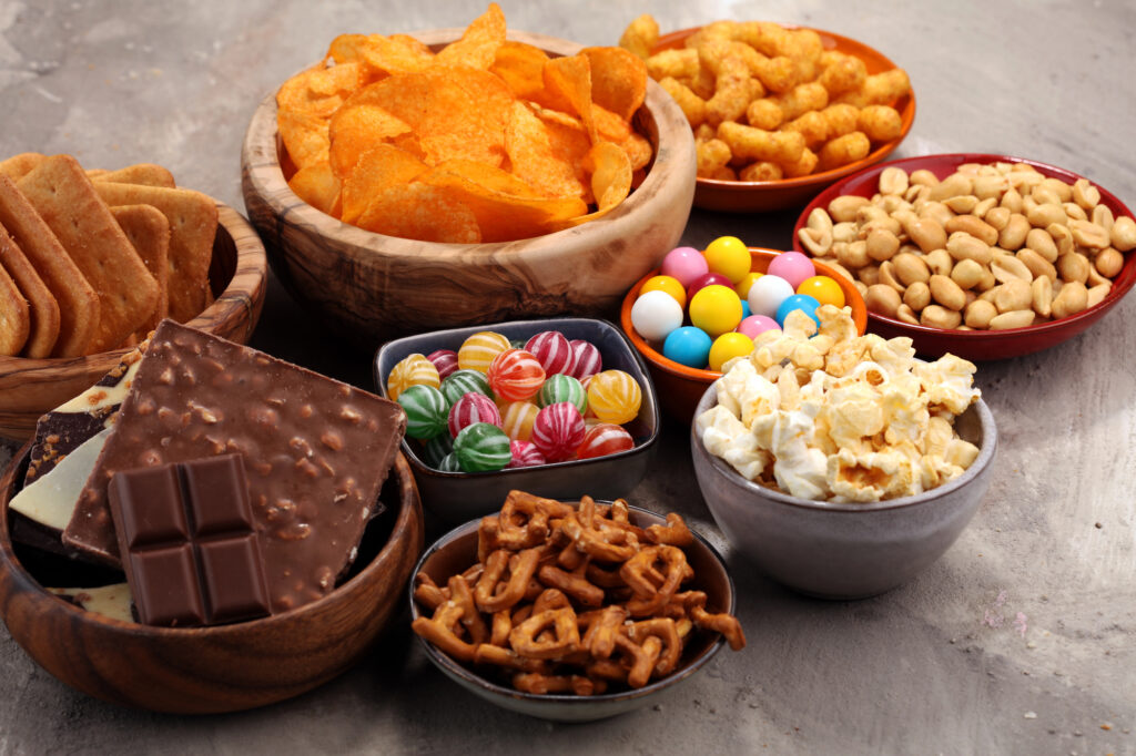 Salty snacks. Pretzels, chips, crackers and candy sweets on table.