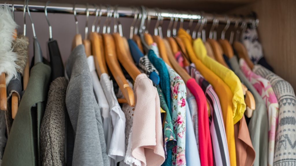 Wardrobe closet full of colorful clothes in dressing-room.