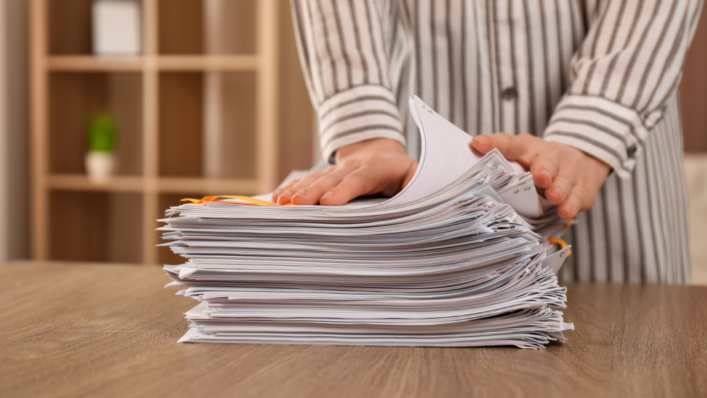 Woman stacking documents at wooden table indoors, closeup