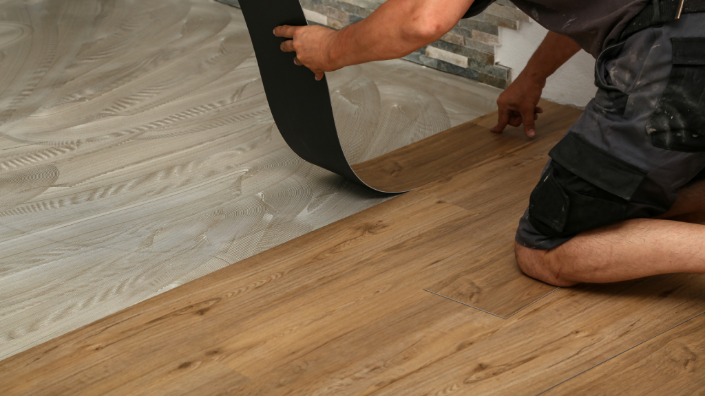 A low angle shot of a worker installing a new set of vinyl tiles on the floor