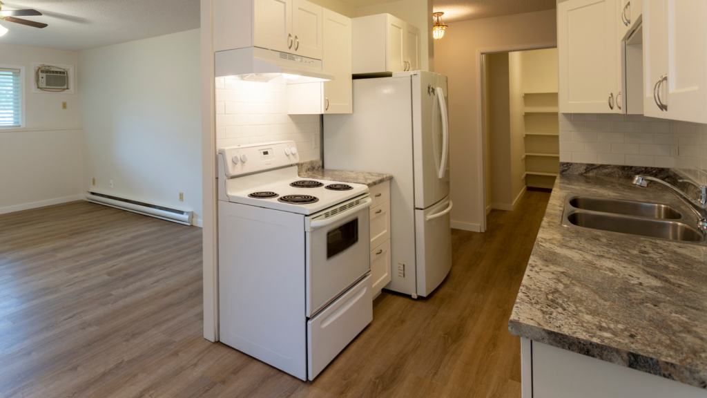 Interior of empty renovated apartment condo rental unit with white walls and new hard wood vinyl laminate flooring