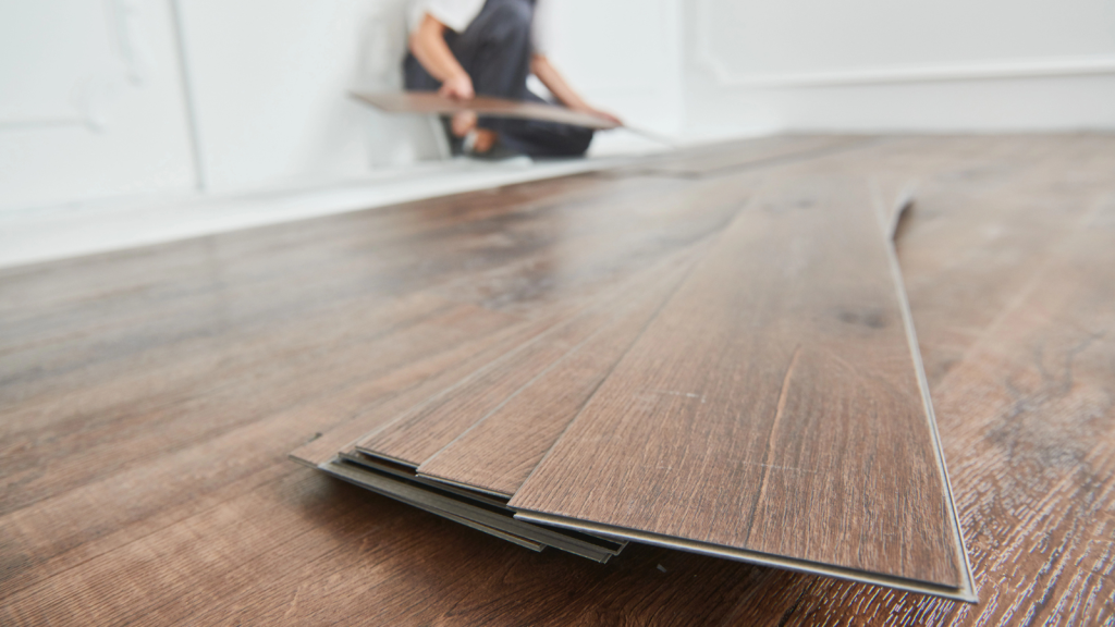 Worker laying vinyl floor covering at home renovation