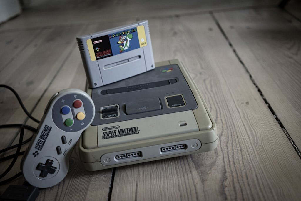 from above of aged video game console with cassette and controller with colorful buttons on wooden surface 4502978