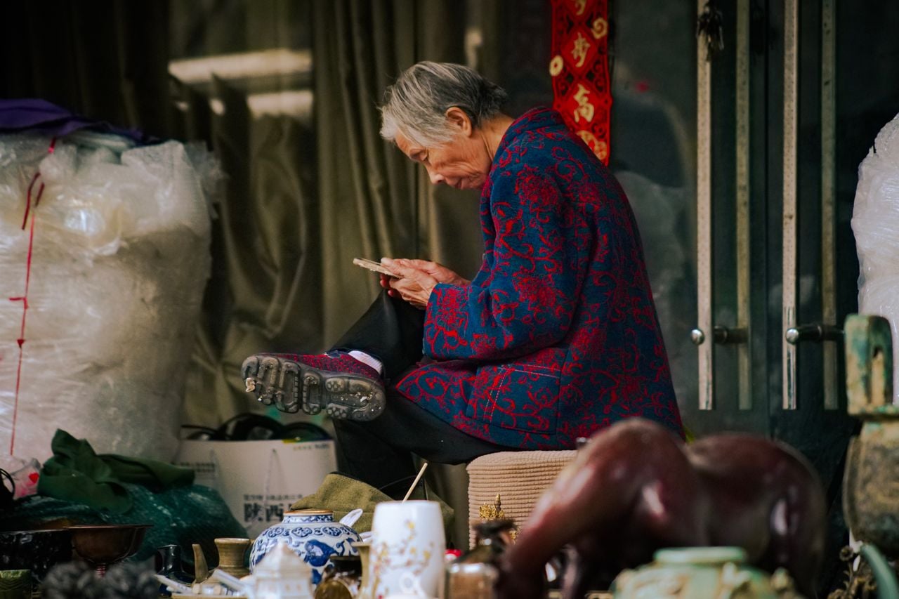 older asian woman in blue and red jacket